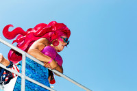 Drag performer in vibrant costume descending a ferry during the annual Invasion of the Pines celebration on Fire Island, photographed by Koitz.