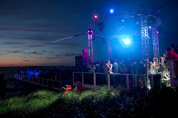 People dancing at the Bay Dance Party in Fire Island Pines, New York, during sunset. Documentary photograph capturing one of Fire Island's iconic LGBTQ+ nightlife events by koitz.