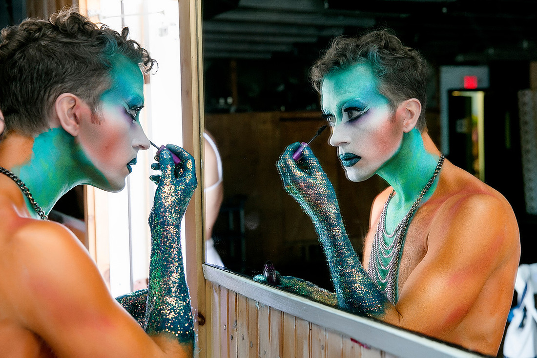 Participant applying dramatic blue and green makeup before the Avatar Invasion of the Pines event in Fire Island Pines, New York, photographed by koitz.