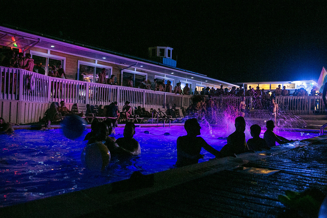 The swimming pool at the Ice Palace in Cherry Grove at night, illuminated against the surrounding darkness and capturing the atmospheric setting of the iconic Fire Island nightlife venue, photographed