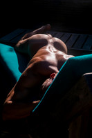 A nude person sunbathes face down on a cushioned lounge chair in Cherry Grove, Fire Island, during a sunny summer afternoon.