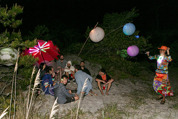 Partygoers gather for the Slanty Party in the Meat Rack on Fire Island, surrounded by the dense natural landscape of the island while socializing and celebrating in a lively outdoor setting, photograp