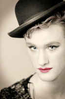 Close-up portrait of Ian wearing a black hat and sequined top, with red lipstick, photographed by koitz.