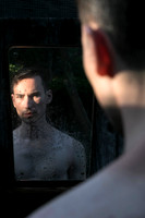 Model looking at himself in a mirror in a queer gay photography portrait by koitz.