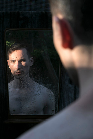 Model looking at himself in a mirror in a queer gay photography portrait by koitz.
