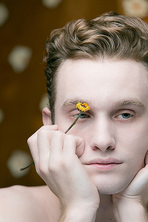 Male model holding flowers in an artistic queer gay portrait by photographer koitz.