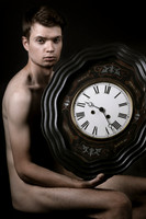 Model posing beside a large clock in a queer gay photography portrait by koitz.