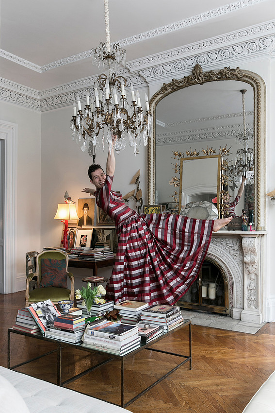 Brock wearing a dress while hanging from a chandelier during an editorial fashion photoshoot.