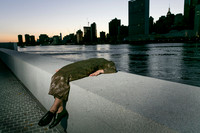 Brock wearing a dress on Governors Island with the New York City skyline in the background.