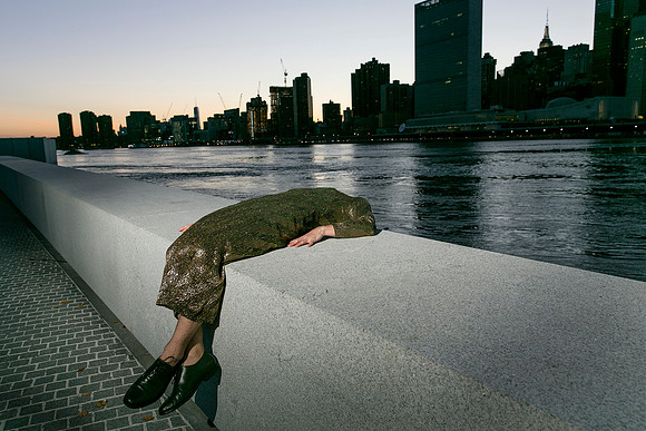 Brock wearing a dress on Governors Island with the New York City skyline in the background.