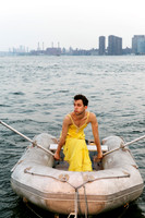 Brock wearing a dress while sitting on a dinghy, photographed by koitz.