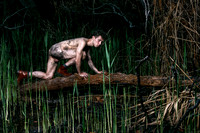 Brock kneeling on a burnt branch among the charred trees of the Meat Rack on Fire Island, photographed by koitz.
