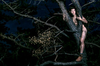 Brock looks through two charred branches in the Meat Rack on Fire Island, photographed by koitz as part of his queer fine-art photography series.